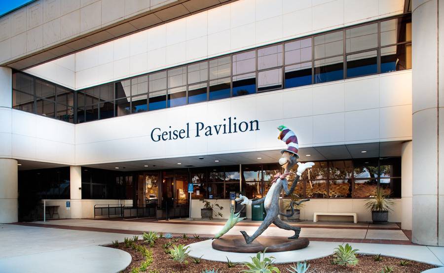 The outside of Geisel Pavilion, which houses Scripps Clinic Torrey Pines Urgent Care, with Dr. Seuss Cat in the Hat statue to the right of the doors.