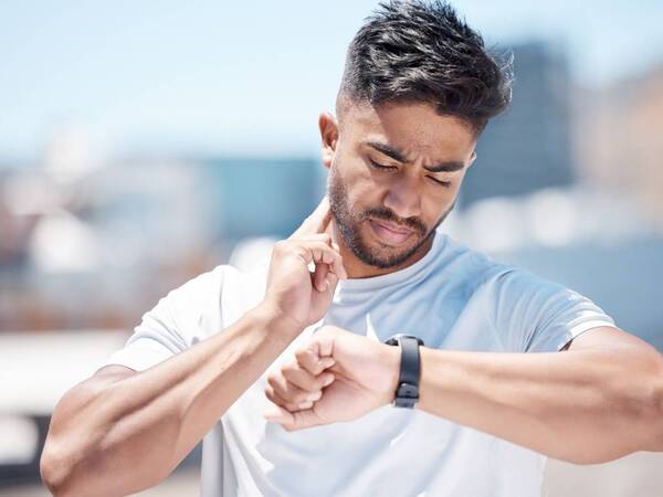 A man checks on his heart rate using a wearable device after working out.